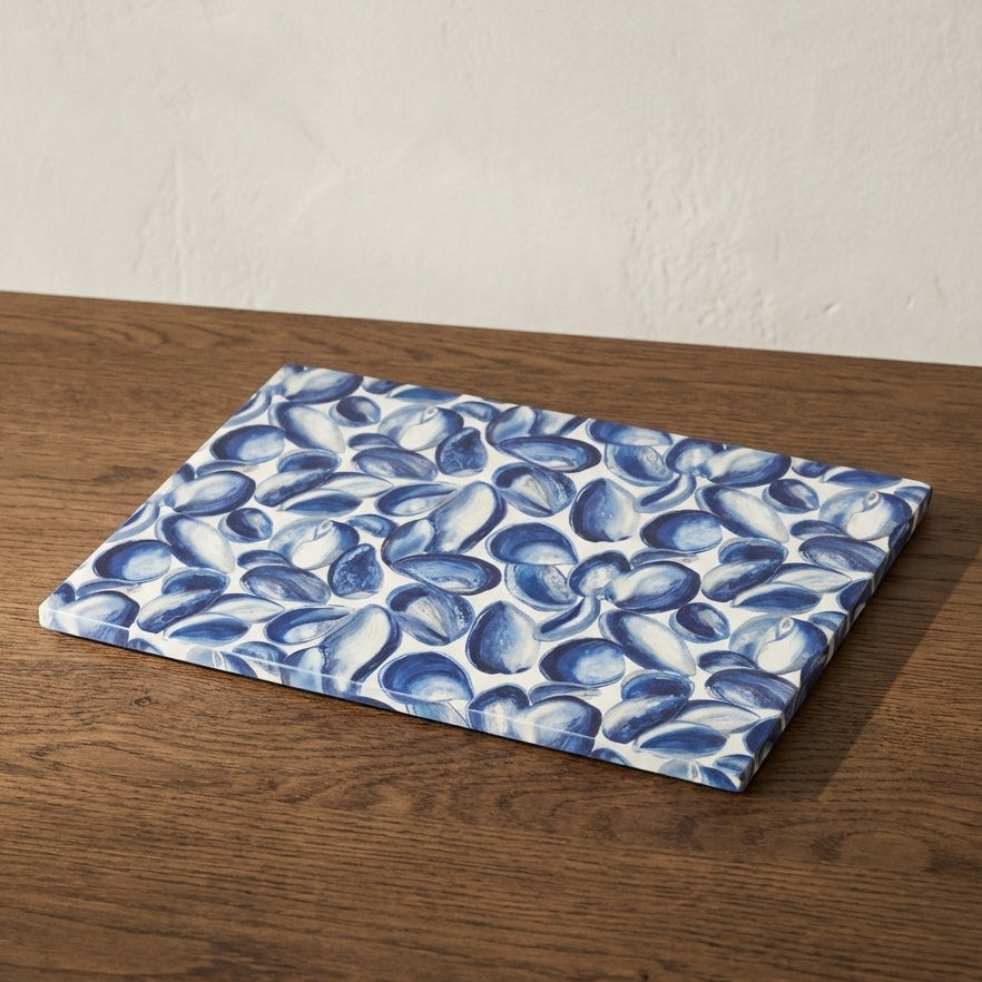 Blue and white mussel shell patterned placemat on a wooden table with a white wall backgroundl 